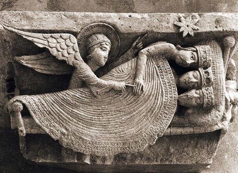 A Romanesque stone relief: an angel touches the hand of one of three crowned kings sleeping under a single blanket