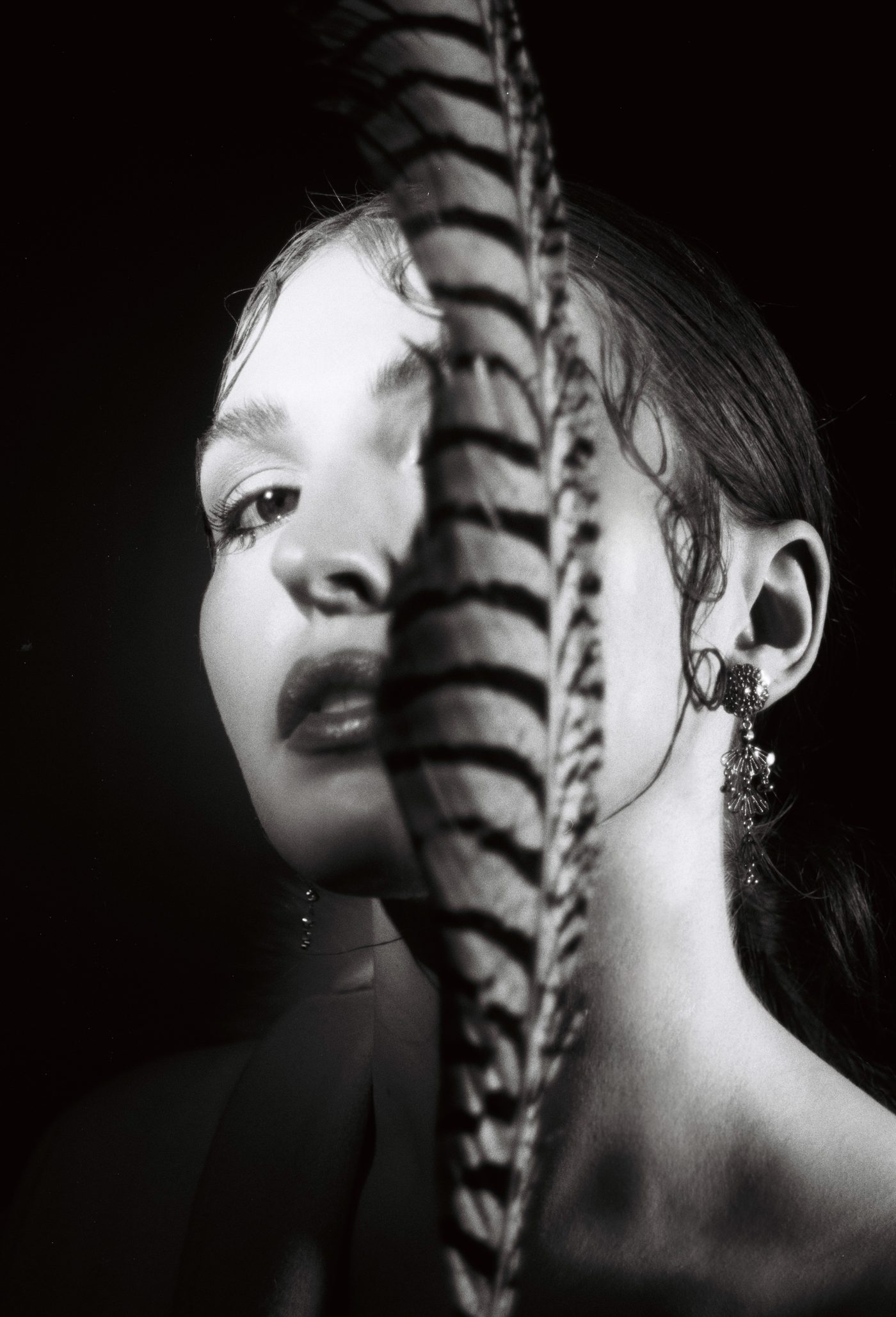 Black-and-white portrait of Marieke McKenna half hidden behind a striped feather