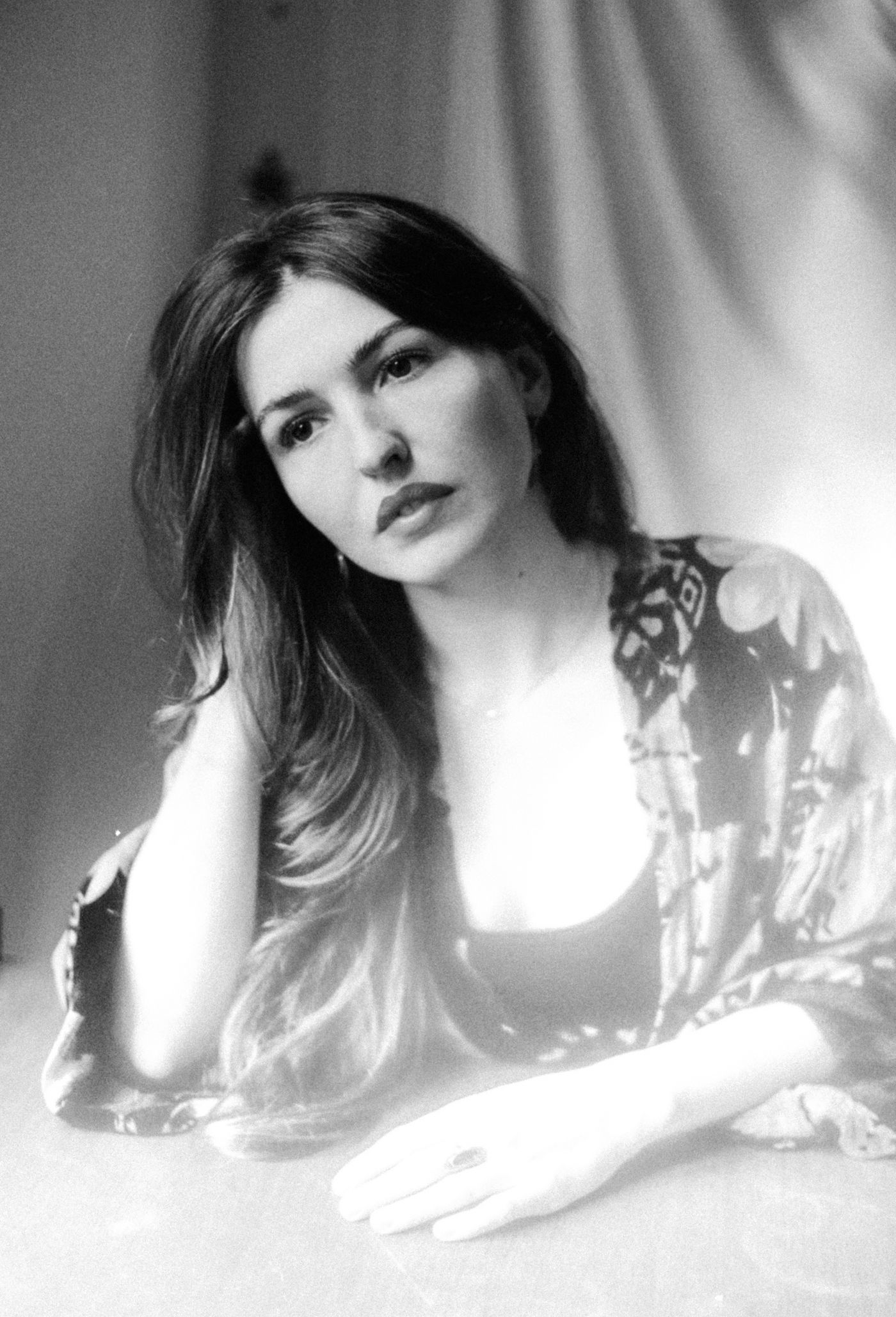 Black-and-white portrait of Marieke McKenna leaning on a table, her hand in her hair