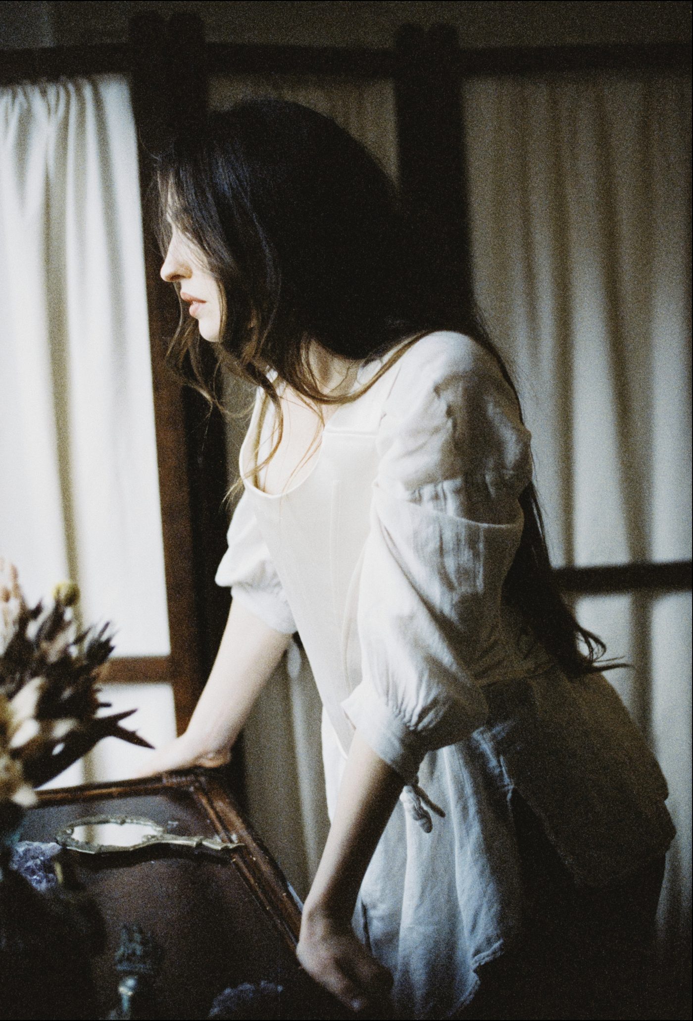 Marieke McKenna in a white blouse by a window, seen in profile